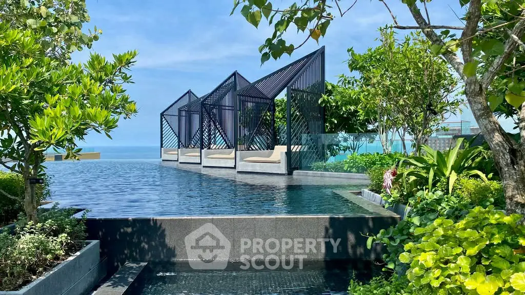 Luxurious rooftop pool with modern cabanas and ocean view, surrounded by lush greenery.