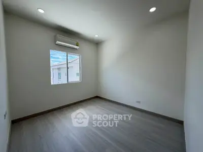 Spacious empty room with wooden flooring and natural light, perfect for customization.