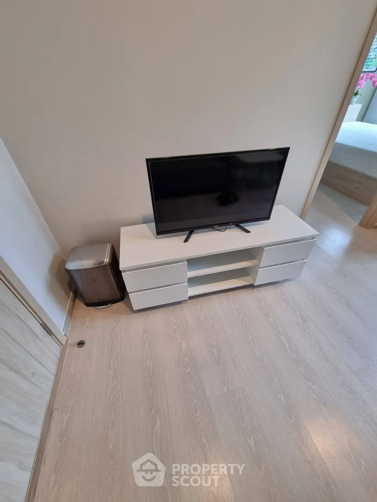 Modern living room with sleek TV stand and flat-screen TV, showcasing minimalist design and light wood flooring.