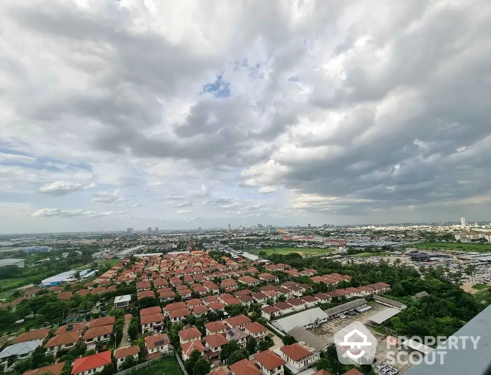 Stunning aerial view of suburban neighborhood with red-roofed houses under dramatic cloudy sky.