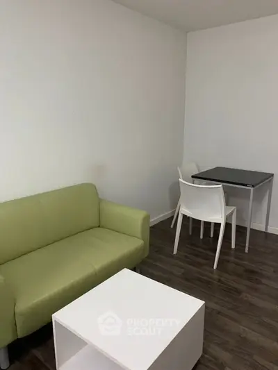 Minimalist living room with green sofa and modern dining table set.