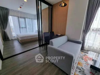Modern apartment interior with stylish living room and bedroom separated by glass partition.
