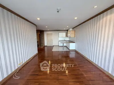 Spacious open-plan living room with wooden flooring and modern kitchen