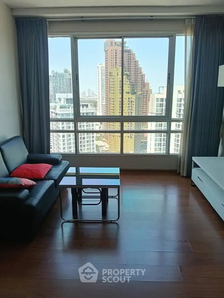 Modern living room with city view, featuring sleek furniture and large windows for natural light.