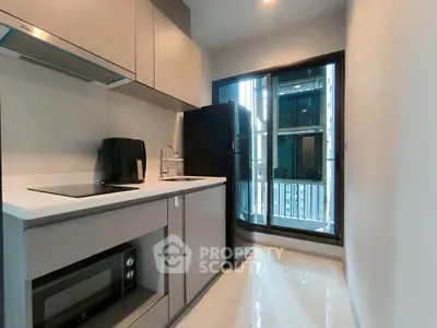 Modern kitchen with sleek appliances and balcony view in urban apartment