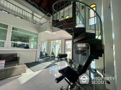 Modern gym with spiral staircase and fitness equipment in bright, spacious interior