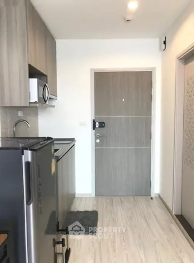 Modern apartment entrance with sleek kitchen and wooden flooring