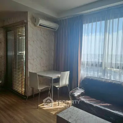 Modern living room with large window and stylish furniture, featuring a cozy seating area and dining table.