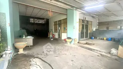 Spacious industrial-style garage with high ceiling and open layout, ideal for storage or workshop use.
