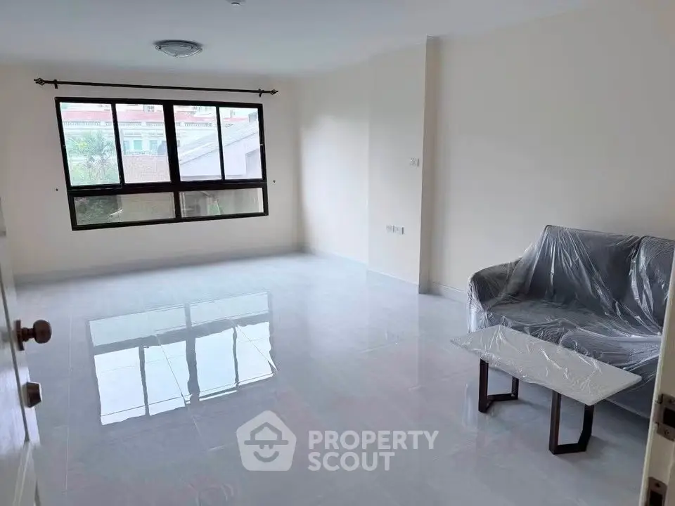 Spacious living room with large window and modern furniture in a bright apartment.