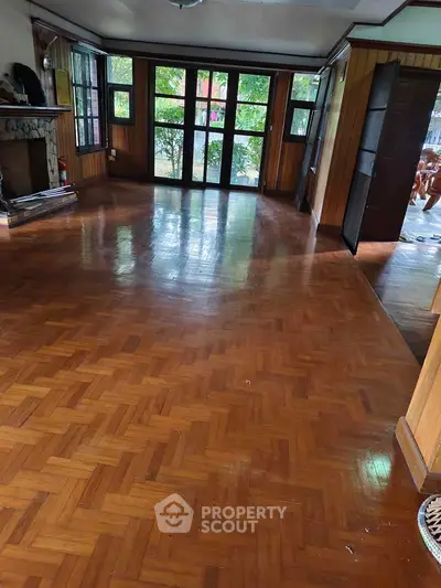Spacious living room with wooden flooring and large windows offering natural light.