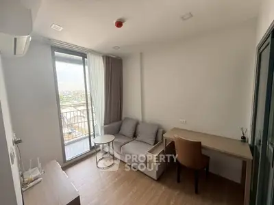 Modern living room with balcony view, featuring cozy sofa and workspace, ideal for urban living.
