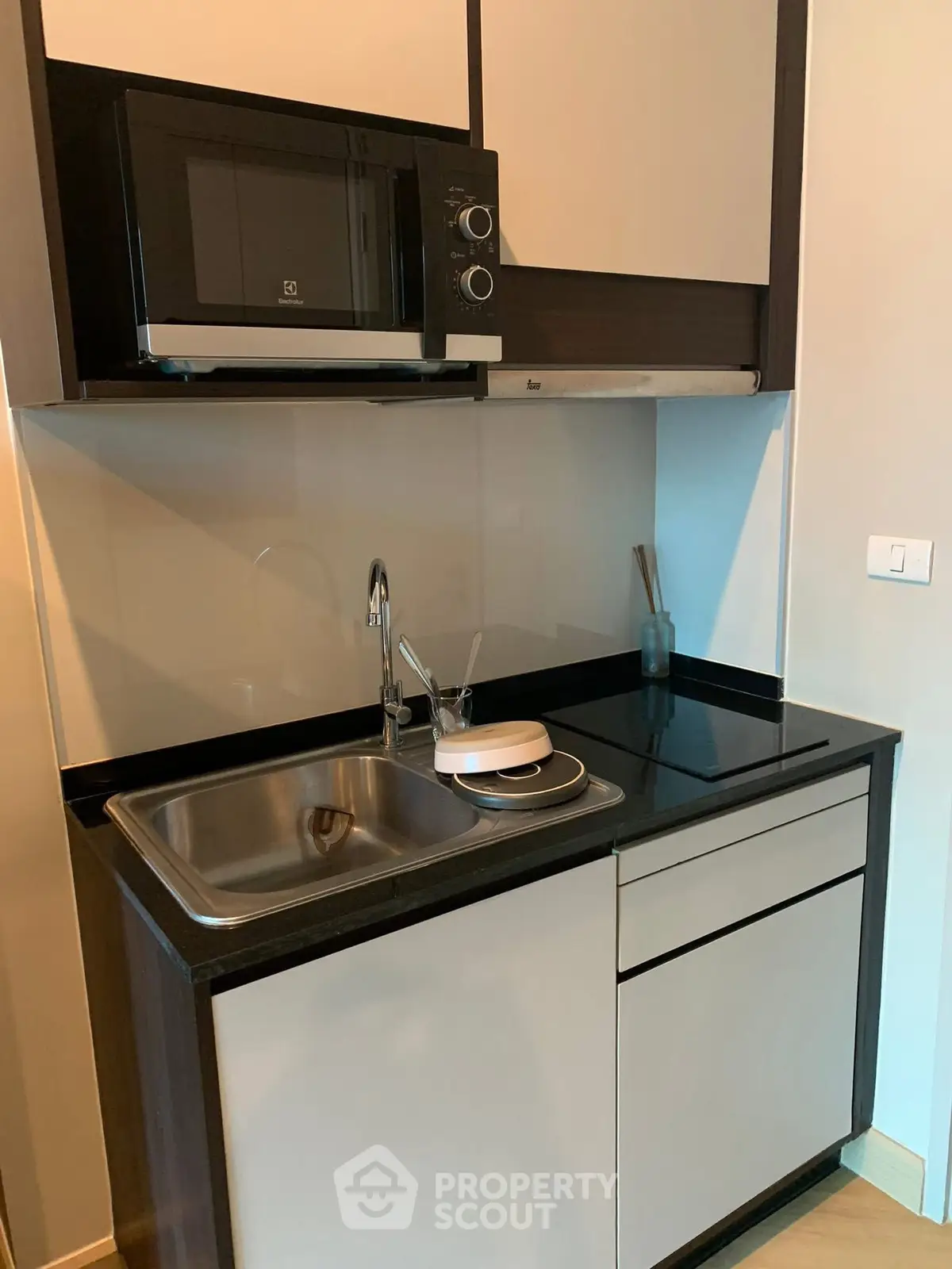 Modern compact kitchen with sleek cabinetry and built-in microwave, ideal for urban living.