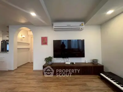 Modern living room with wall-mounted TV and air conditioning, featuring stylish wooden flooring and elegant decor.