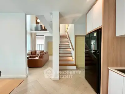 Modern duplex interior with stylish staircase and open living area featuring sleek kitchen design.