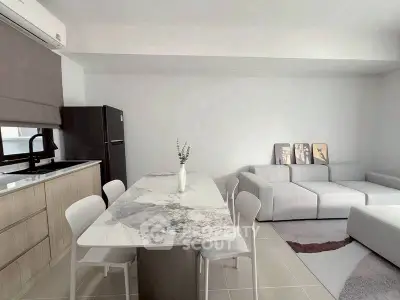 Modern open-plan kitchen and living room with sleek marble dining table and cozy gray sofa.