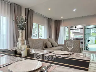 Elegant modern living room with dining area, featuring stylish decor and large windows for natural light.