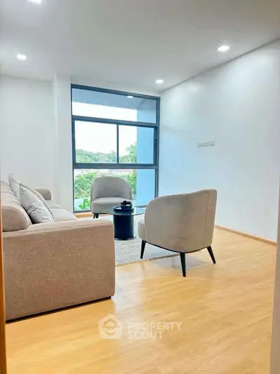 Modern living room with large window and stylish furniture, offering a bright and inviting atmosphere.