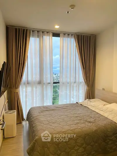 Modern bedroom with large window offering stunning city view, elegant curtains, and cozy bedding.
