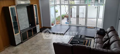 Spacious living room with leather sofa and large windows opening to patio