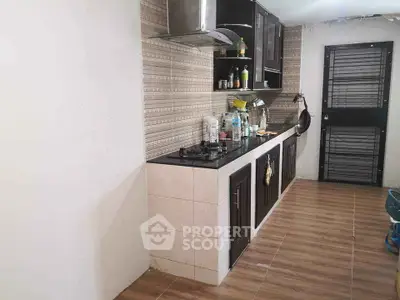 Modern kitchen with sleek cabinets and gas stove, featuring a stylish backsplash and wooden flooring.