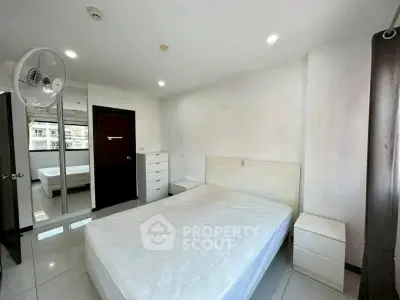 Spacious bedroom with modern furniture and large window view.