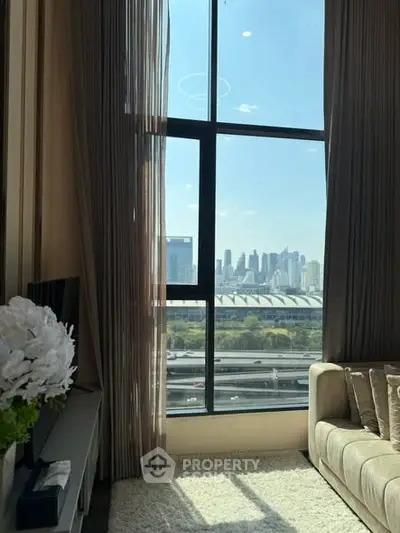 Luxurious living room with floor-to-ceiling windows offering stunning city skyline views.