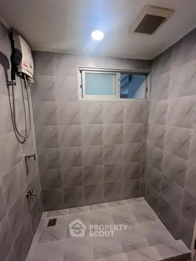 Modern bathroom with sleek gray tiles and overhead shower in a contemporary home.