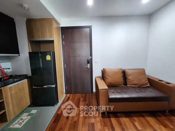 Modern apartment interior with sleek kitchen and cozy living area featuring wooden flooring and stylish furniture.