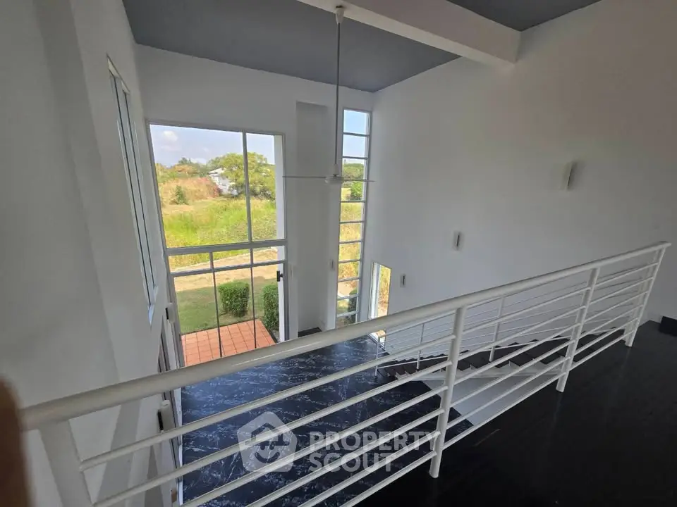 Modern two-story home with large windows and sleek railing, offering scenic views.