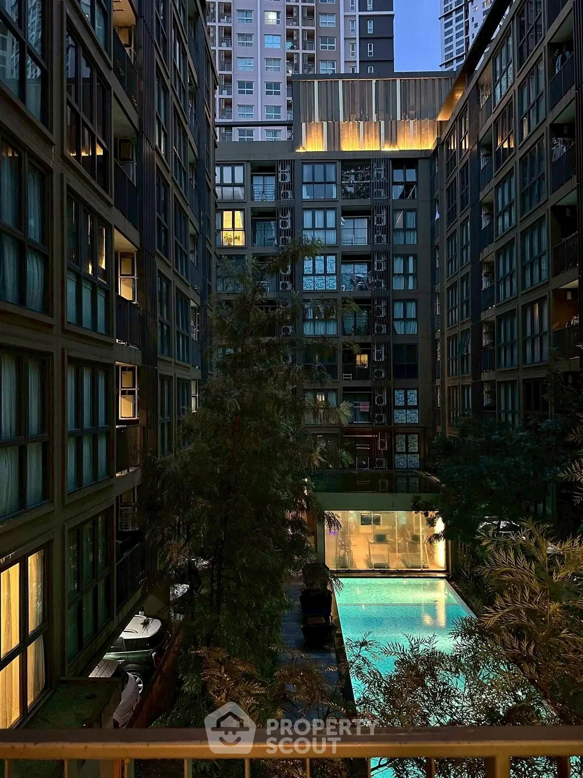 Stunning urban apartment complex with illuminated pool and modern architecture.