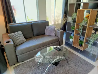 Modern living room with stylish sofa, glass coffee table, and decorative shelving unit.