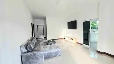 Spacious modern living room with sleek furniture and large TV, perfect for relaxation.