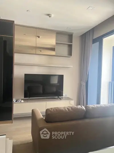 Modern living room with sleek TV setup and large window for natural light.