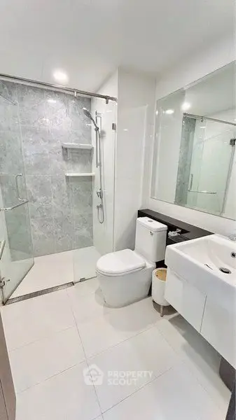 Modern bathroom with glass shower and sleek fixtures in a contemporary apartment.