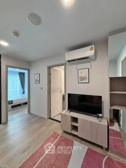 Modern living room with TV and air conditioning, adjacent to a cozy bedroom with natural light.