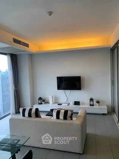 Modern living room with sleek design, featuring a wall-mounted TV and ambient lighting.