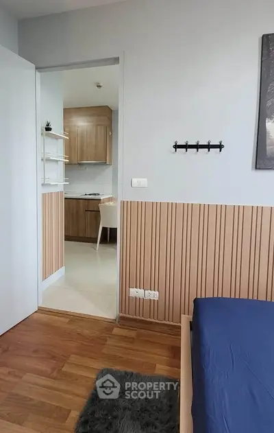 Modern bedroom with wooden accents and view into a compact kitchen