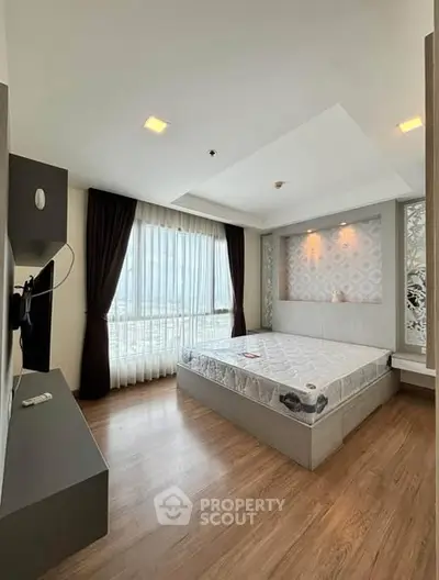 Modern bedroom with large window and stylish decor in high-rise apartment.