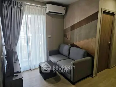 Modern living room with stylish decor, featuring a cozy sofa and natural light from large window.