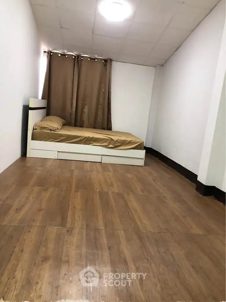 Spacious minimalist bedroom with wooden flooring and simple decor