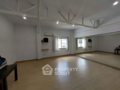Spacious room with wooden flooring and large mirror, ideal for dance or yoga studio.