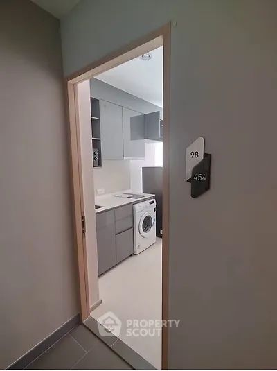 Modern apartment entrance with sleek kitchen and washing machine