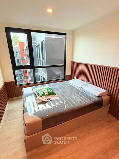 Modern bedroom with large window and stylish wood paneling in urban apartment