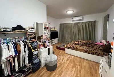 Cozy bedroom with wooden flooring, open closet, and modern decor