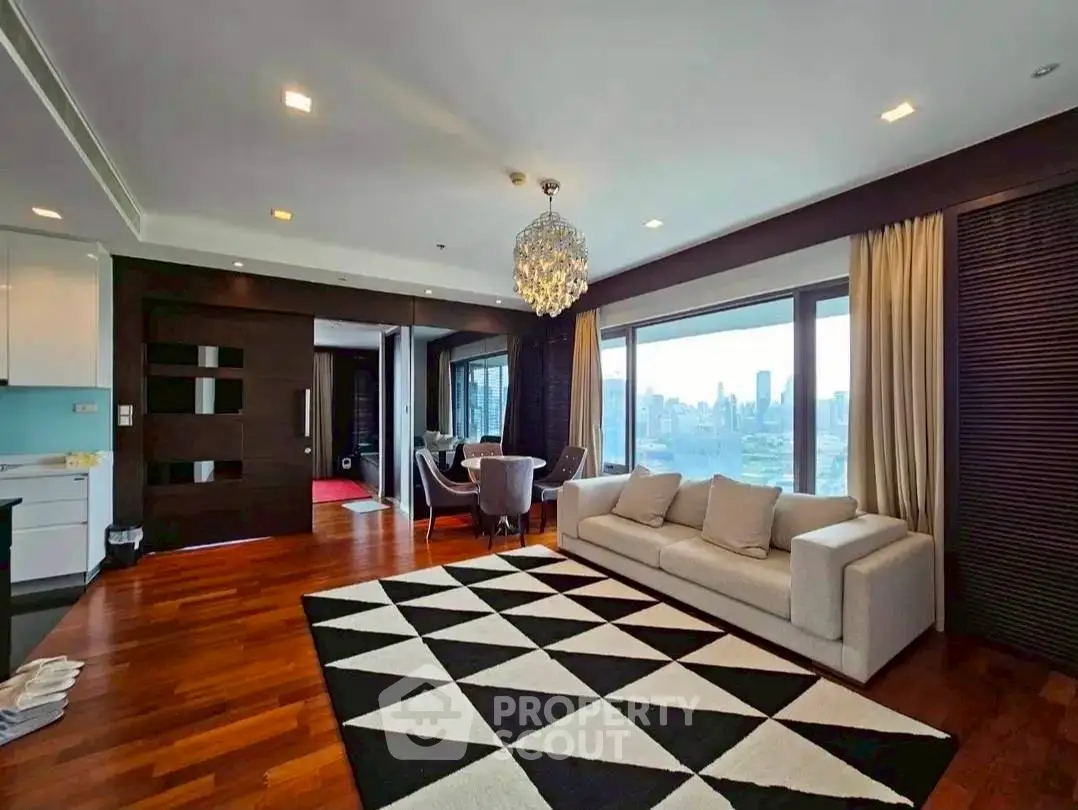 Luxurious living room with stunning city view, elegant chandelier, and modern decor in high-rise apartment.