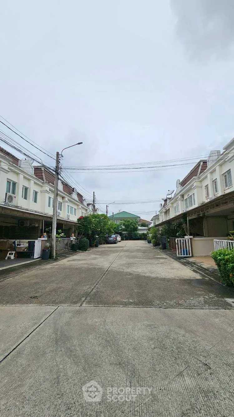 Charming residential street with townhouses and lush greenery, perfect for family living.