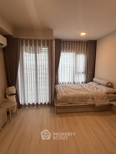 Cozy bedroom with large windows and modern decor in a stylish apartment.