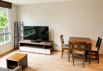 Modern living room with large TV and dining area, featuring sleek furniture and natural light.
