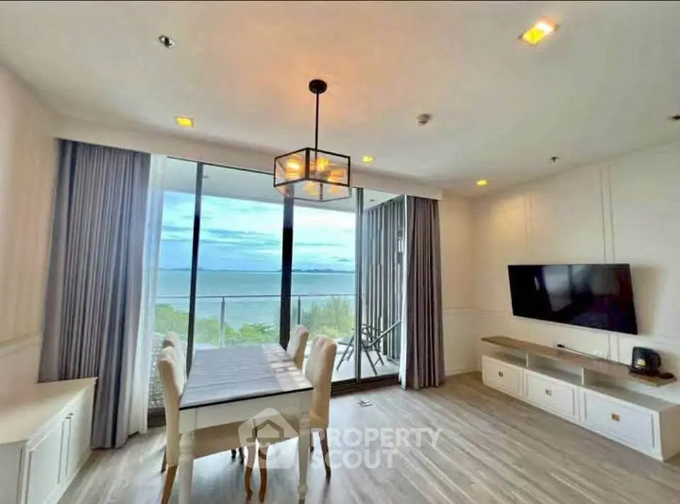 Stunning living room with ocean view, modern decor, and elegant dining area in beachfront property.